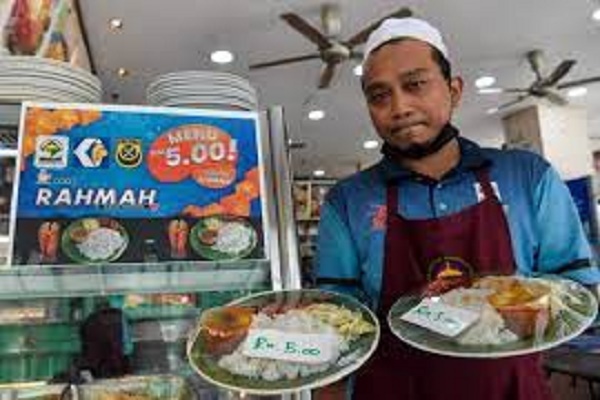 Un employé de restaurant montre un exemple de la nourriture offerte dans le cadre du programme Menu Rahmah dans un restaurant de Kuala Lumpur.